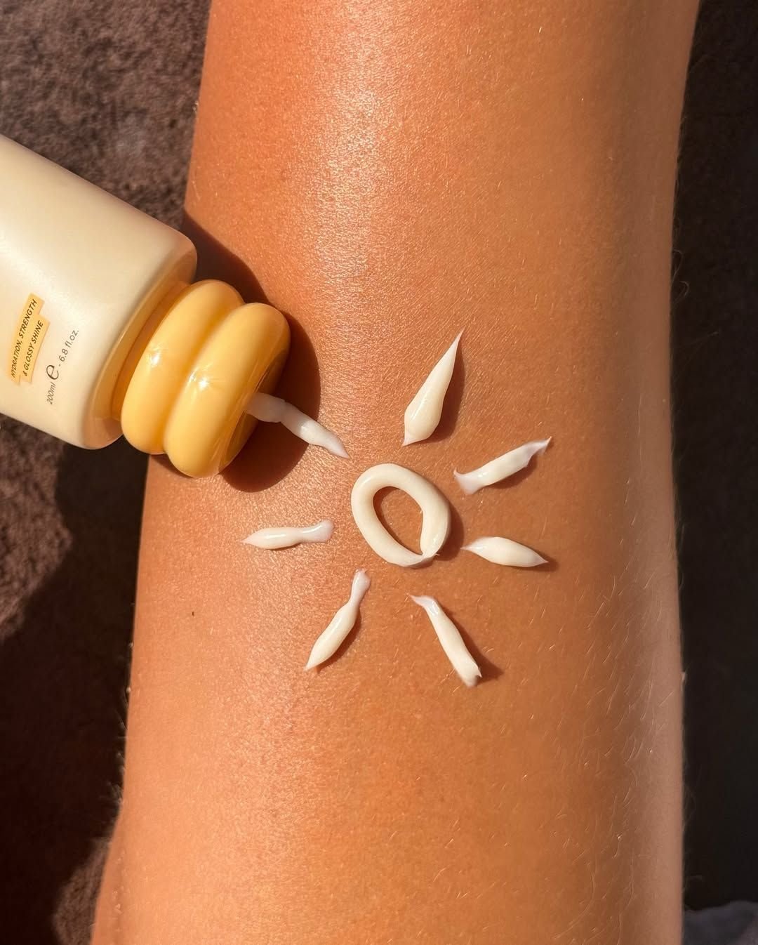 Produit de soin solaire appliqué sur la peau sous une lumière chaude